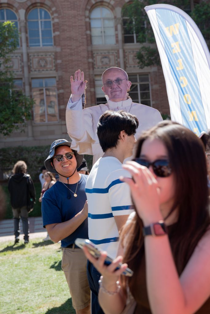 A club officer holds up a life-size poster of Pope Francis to attract new members. In order to stand out from the crowd, clubs use creative ways to draw students' attention. Photo by Julia Gu/BruinLife.