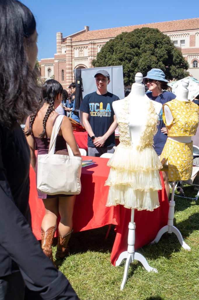 The UCLA Sex Squad displays two dresses at their booth for the Enormous Activities Fair. Both dresses were made by one of the club's interns; one dress is made out of Trojan brand condom wrappers and the other was made out of the actual condoms. Photo by Juan Cesar Perez/BruinLife.