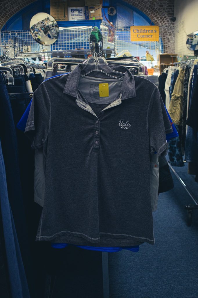 A gray top with a UCLA logo in the top right hangs on a rack. You can also find UCLA apparel with only the UCLA logo at a whopping one-sixth of the original cost. Most items are barely worn and in great condition.