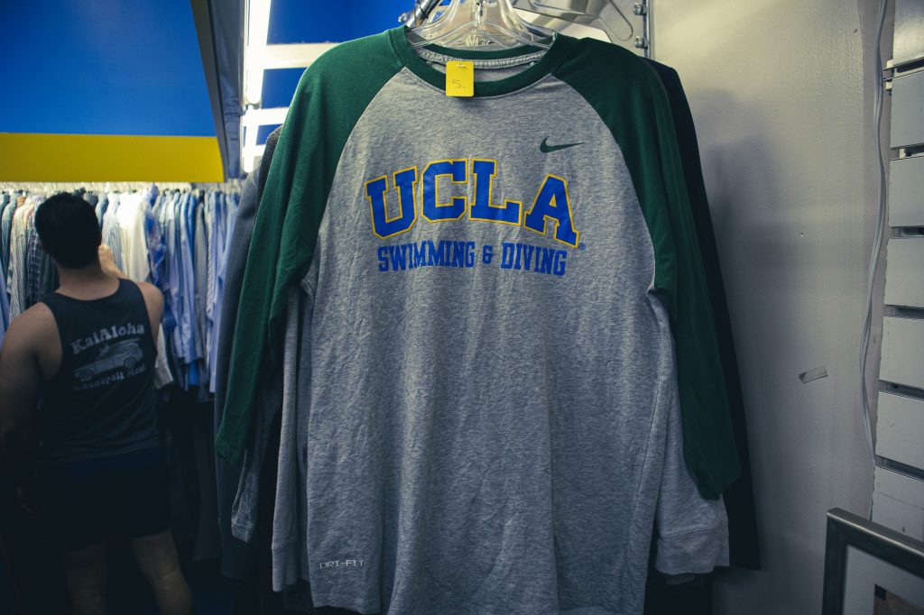 A UCLA Swimming and Diving long-sleeve hangs on a rack inside of the store; a person stands to the left of frame, browsing through the other long-sleeves. There is a range of UCLA merchandise in the thrift shop, some from UCLA athletic teams, so, if you’re lucky enough, you might be able to find something from your favorite UCLA team.