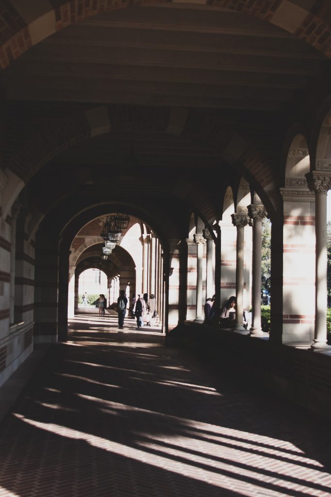 Students walk under the front archways of Royce Hall. The famously beautiful building not only offers these archways as a peaceful place to sit, but it also overlooks the eye-catching view of Powell Library.