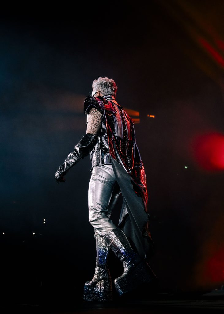 Adorned in a fabulously intricate ensemble, Adam Lambert graced the stage with a presence that absolutely captivated the audience. With the crowd clapping along to the band’s famous anthem “Radio Ga Ga”, the energy within the stadium was palpable.