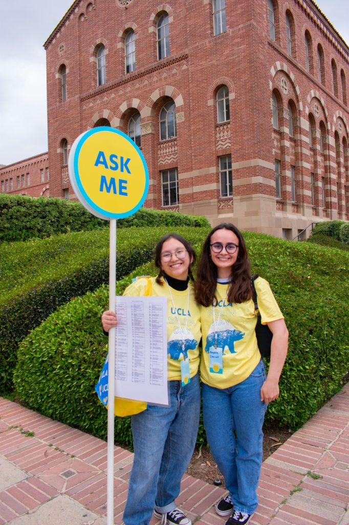 Sylvia Ke (left), a freshman studying education & social transformation, and Hayden Carroll (right), a senior majoring in psychology, hold up an "Ask Me" sign to guide students. “Students seem super excited and a lot of them are already committed, so it’s been a lot of congratulating people and directing them to things they’d need to see," Ke said.
