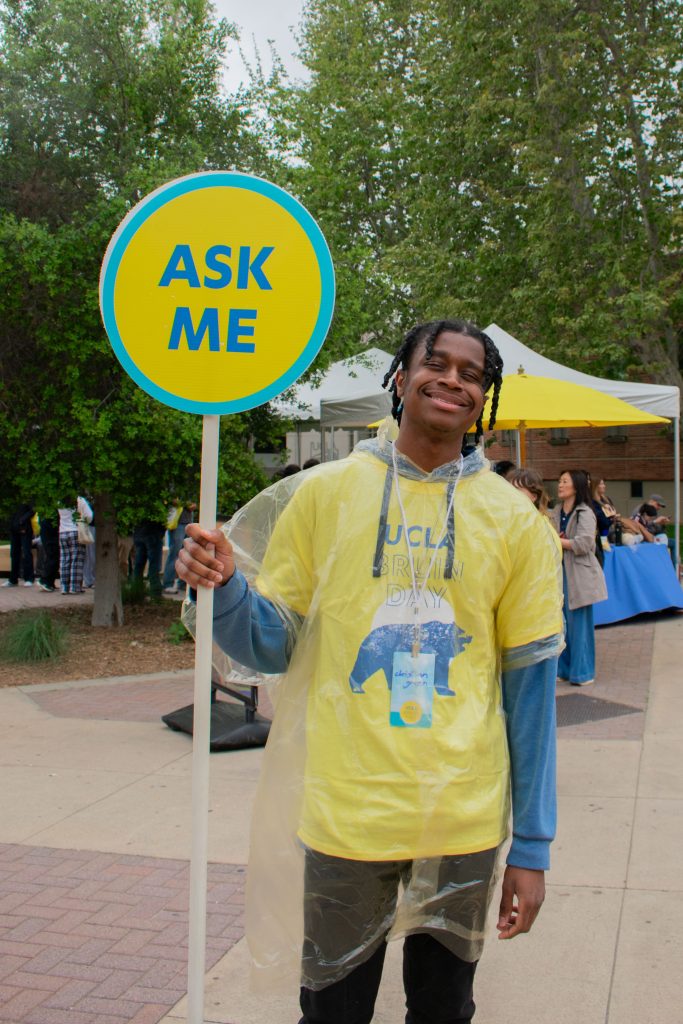 Christian Green, a first-year transfer student majoring in African American studies, holds up an "Ask Me" sign to signal to potential freshman students. “The day’s been good," Green said. "I haven’t been here for too long but I’ve talked to a few students still making their decisions and they seem a little nervous.”