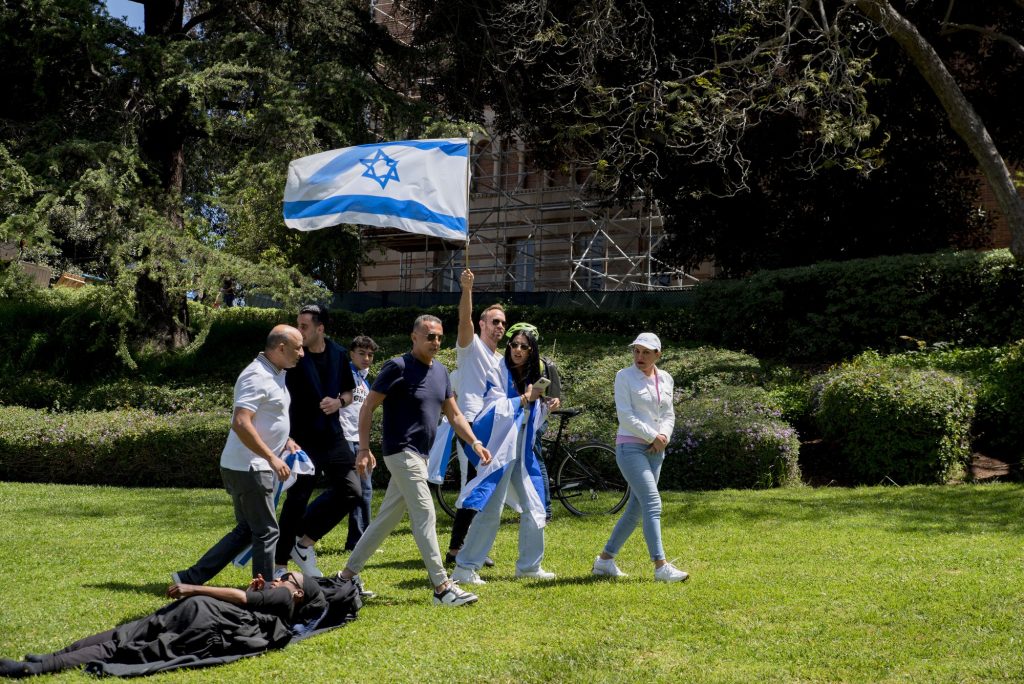 Israeli counter-protesters walk across the grass of Janss/Kuruvungna Steps bearing the flag of Israel. Photographed by Emily Chandler/BruinLife.