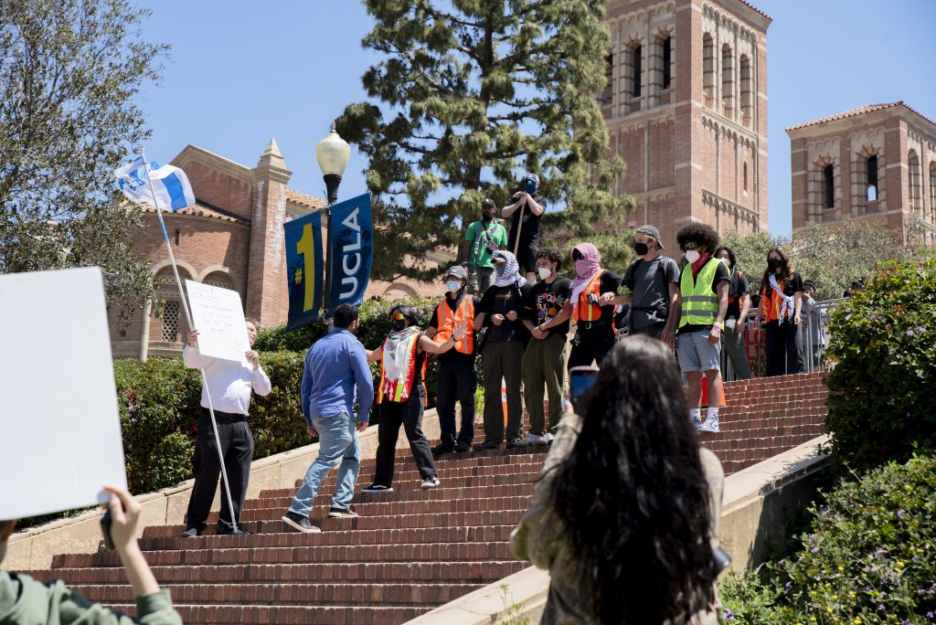 An Israeli counter-protester approaches a line of pro-Palestine protesters on Janss/Kuruvungna Steps. Barriers, created by students inside the encampment, surround Dickson Plaza and block off the top of Janss/Kuruvungna Steps. Photographed by Emily Chandler/BruinLife.
