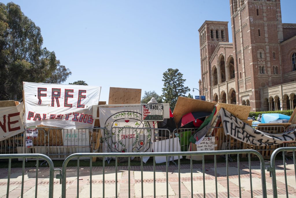 Signs and banners span the side of the makeshift barrier constructed by students within the encampment. Photographed by Emily Chandler/BruinLife.