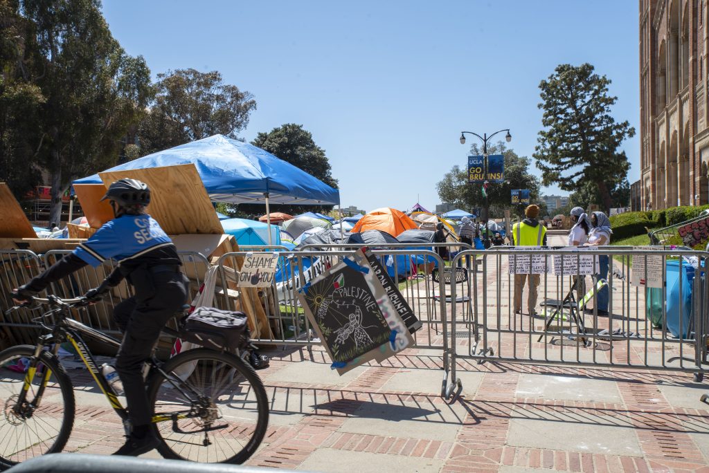 University security patrol the walkway between the encampment and the rest of Dickson Plaza. Students within the encampment can be seen monitoring the area. Photographed by Emily Chandler/BruinLife.