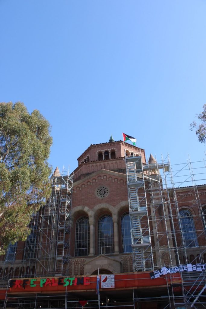 The flag of Palestine flies freely atop the rotunda of Powell Library. Encampment protestors extended their control to the front of Powell and its scaffolding. Photograph provided by the Encampment Document Team.
