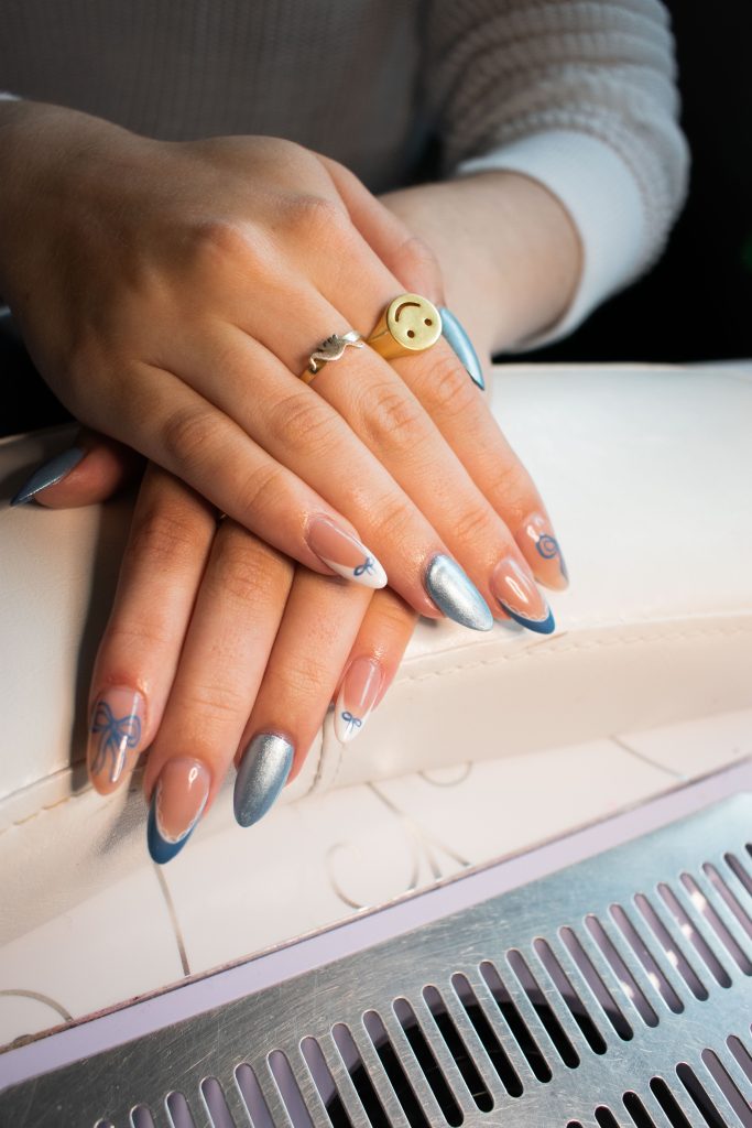 Client shows off her nail set done by Mia Pryzbus: a blue and chrome based “coquette” themed set.
Photographed by Emily/BruinLife