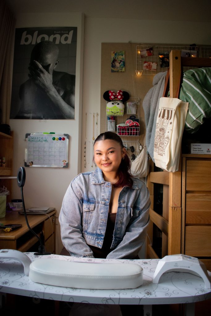 Mia Pryzbus smiles in her dorm in front of her nail station. This is the workspace she has created to do fellow UCLA students' nails.
Photographed by Emily Chandler/BruinLife