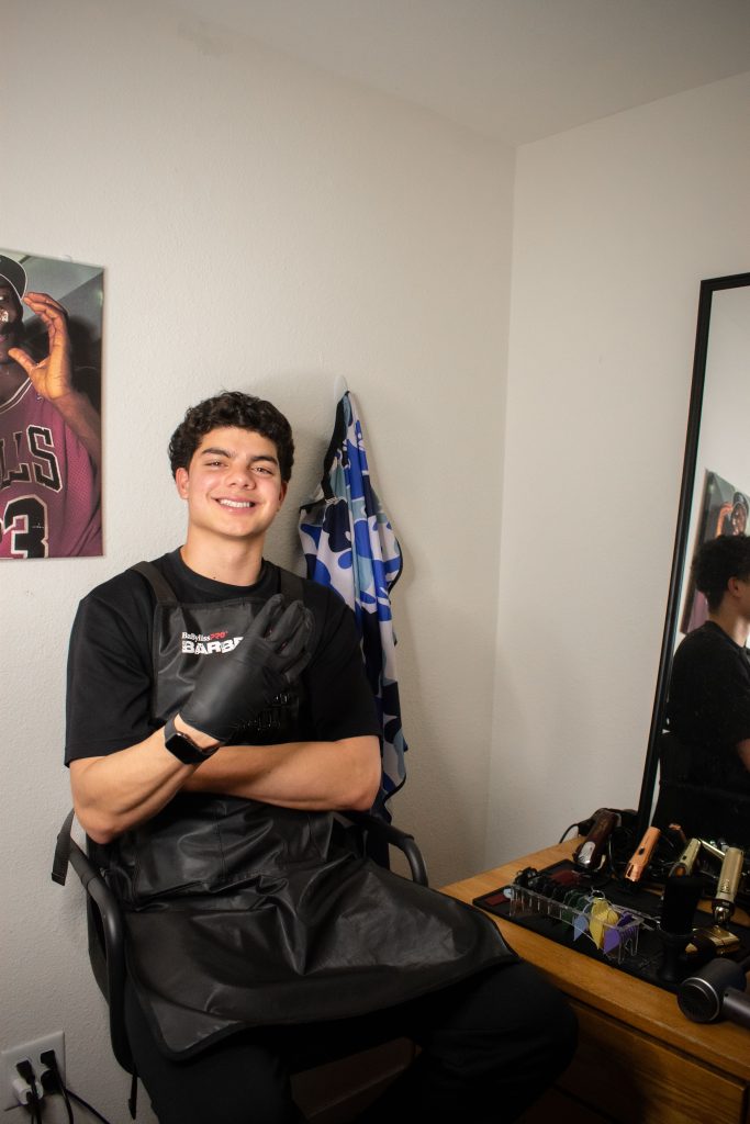 Diego Duarte smiles at the camera as he sits in his own barber chair. He held up a “4” as a homage to the notorious “4s up.”
Photographed by Emily Chandler/BruinLife
