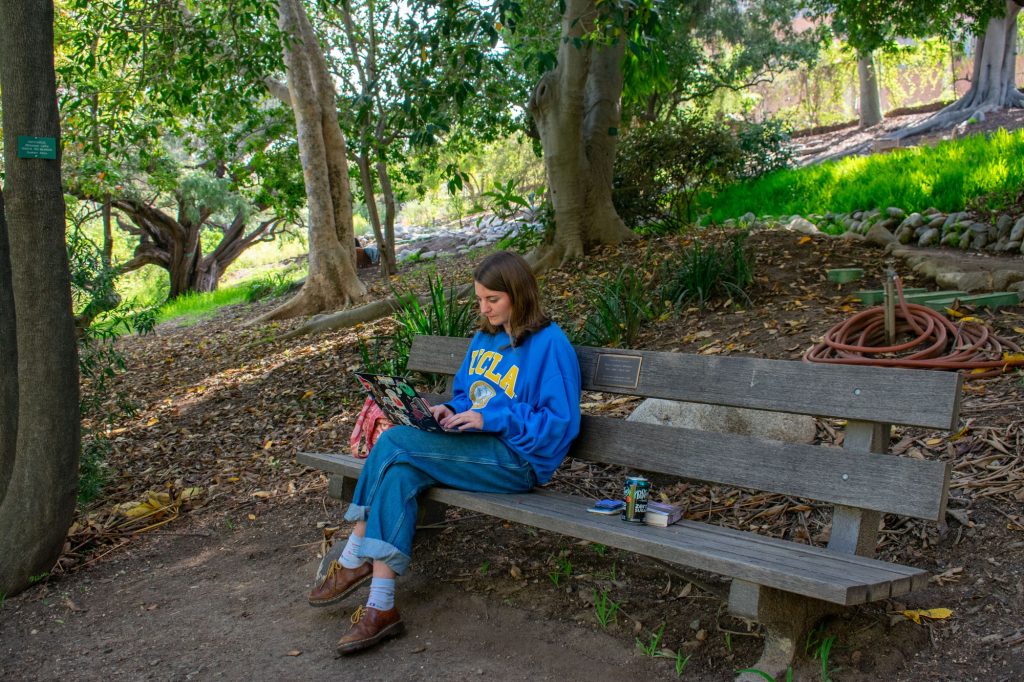 Chloe Millar, a fourth-year student studying political science and anthropology, sits on a bench studying at the Botanical Garden.
