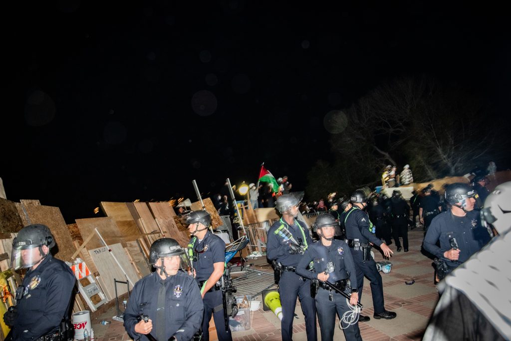 Police in riot gear holding flash-bang guns, batons and zip-tie handcuffs breach the Palestine solidarity encampment from the Janss/Kuruvungna Steps entrance. Law enforcement broke past student lines, making arrests and passing the physical barricade that guarded the encampment. Photographed by Finn Martin/BruinLife.
