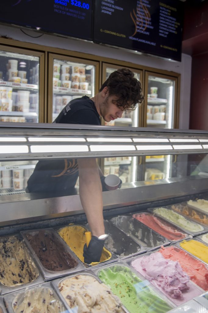 An employee at Saffron and Rose scoops out a ball of the store's homemade Saffron Pistachio ice cream, made with natural ingredients. Saffron and Rose has always been a family business.