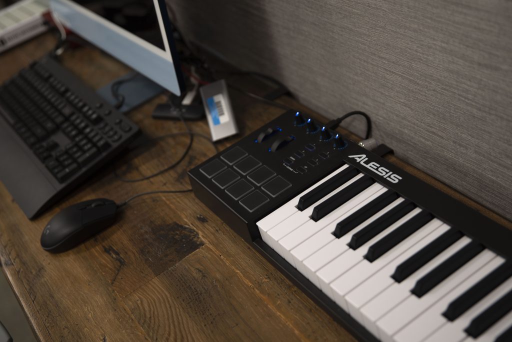 An Alesis V25 MIDI controller glows in blue backlight. Each lab station is equipped with a keyboard, an audio interface and a desktop computer with a plethora of editing and production software. Photographed by Julia Gu/BruinLife