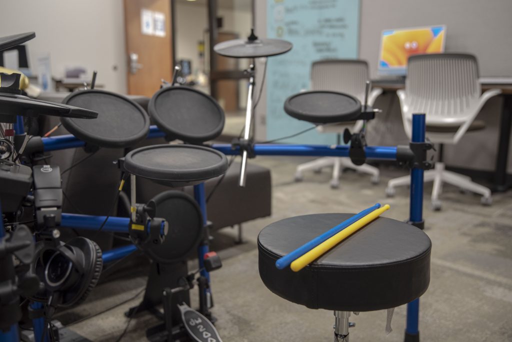A pair of blue and yellow drumsticks lie on the seat of an electric drum set. The set is a popular addition to the lab room. Photographed by Julia Gu/BruinLife