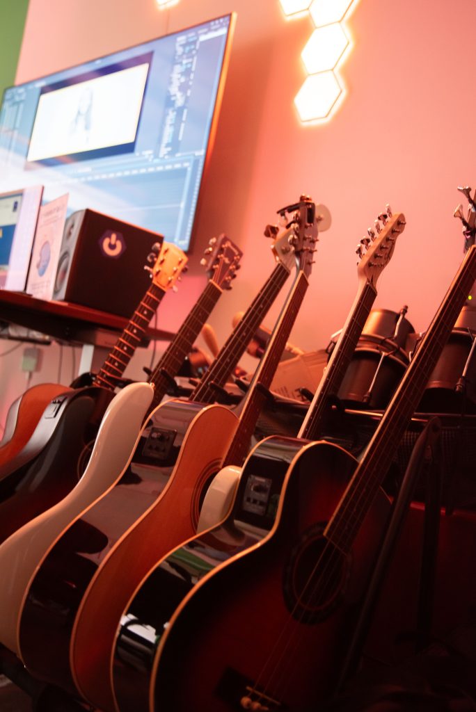 An assortment of guitars are lined up against a warmly lit wall in the De Neve Learning Center for students to experiment with and create their own music. Photographed by Julia Gu/BruinLife