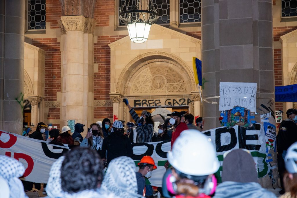 Protesters prepare to reinforce the doors of Royce Hall in anticipation of police breaching the encampment. Posters and graffiti were scattered across the walls of Royce. Photographed by Caleb Velasquez/BruinLife.