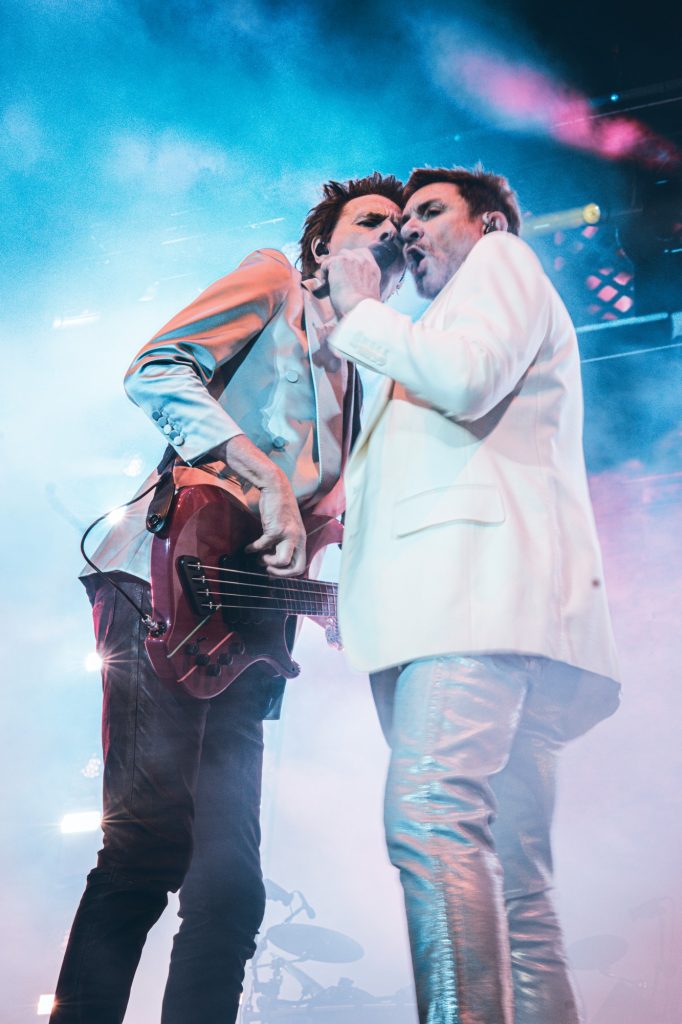 Duran Duran band members John Taylor and Simon Le Bon share a note as they cause the crowd to erupt in excited screams. Photographed by Cathryn Kuczynski/BruinLife