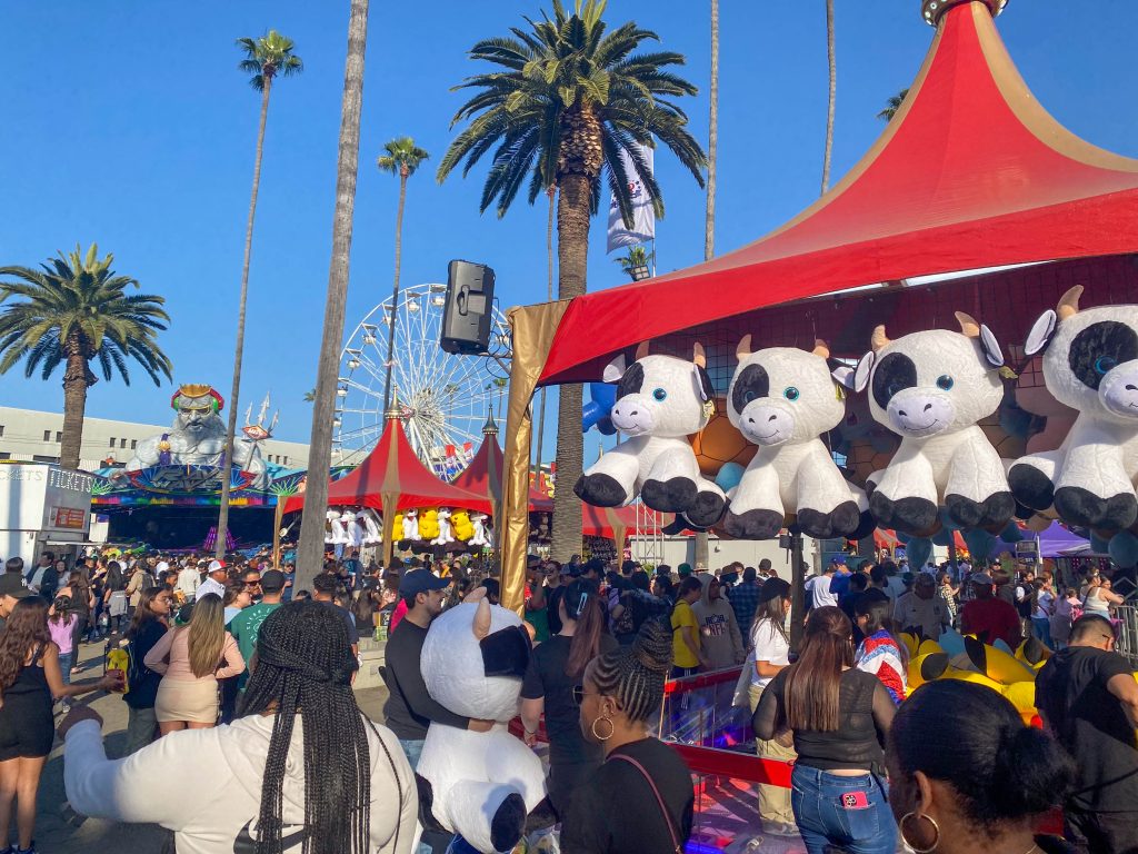 Giant cow stuffed animals hang from the game tents, inviting people to try and win them as prizes.