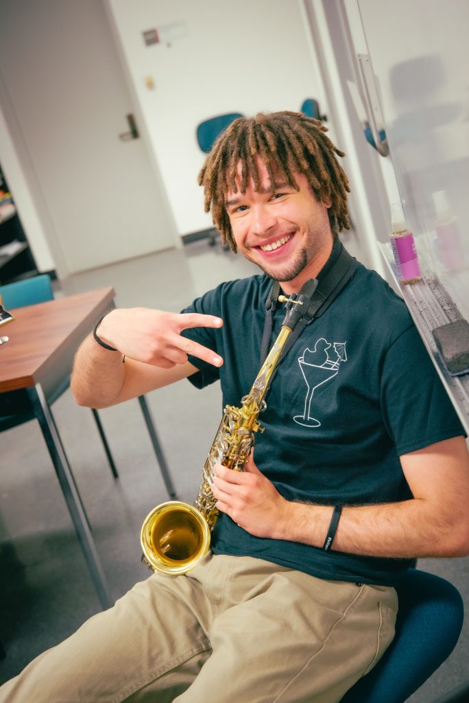 Stafford Williams, a third year neuroscience major and saxophonist, takes a pause between beats to greet the camera.  Photographed by BruinLife/Finn Martin