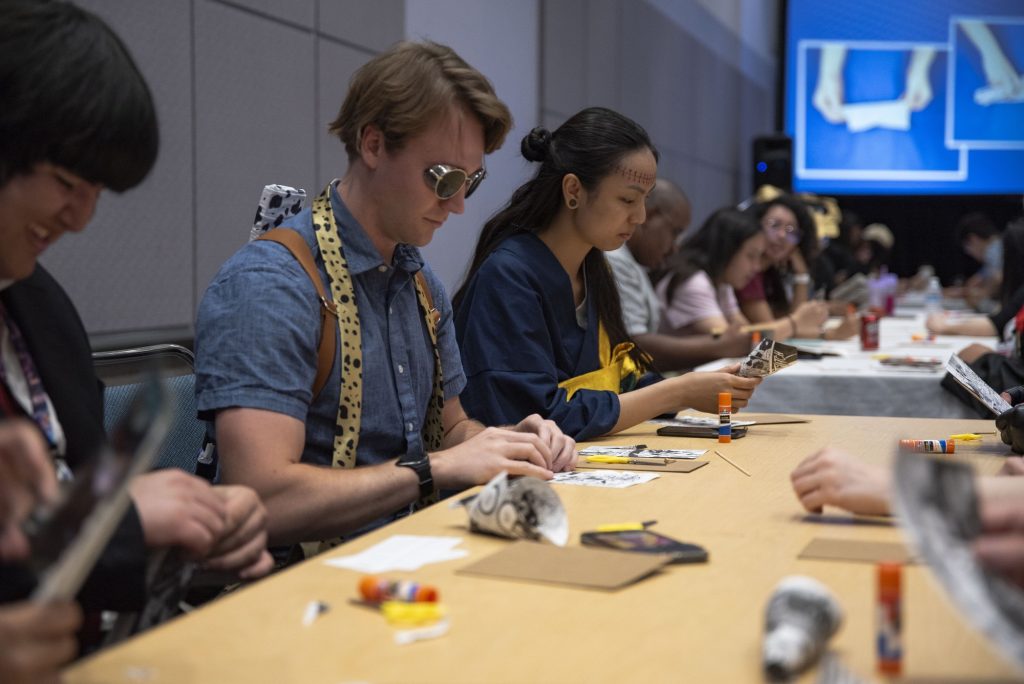 Chris U., dressed up as Nanami from the popular anima Jujutsu Kaisen, follows the directions to make his own wall art piece at a workshop on day two. Photographed by Caleb Velasquez/BruinLife.