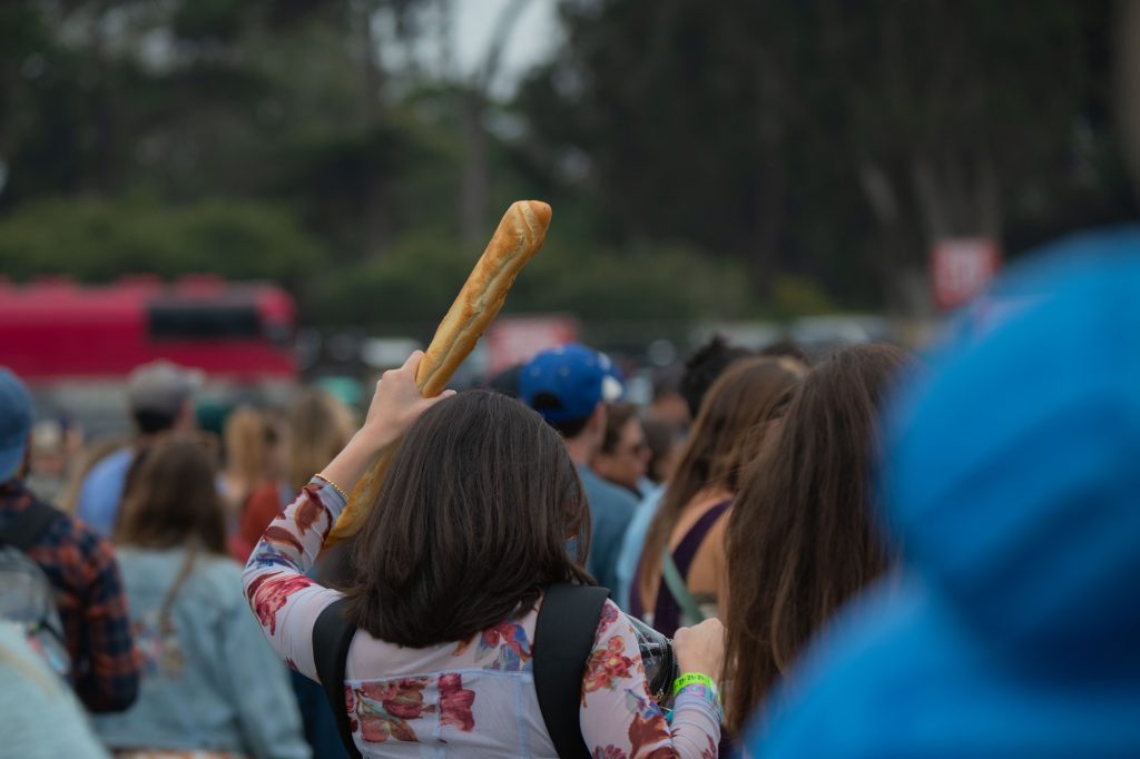 An attendee holds up a baguette as a totem at Lands End stage. Photographed by Caleb Velasquez/BruinLife.