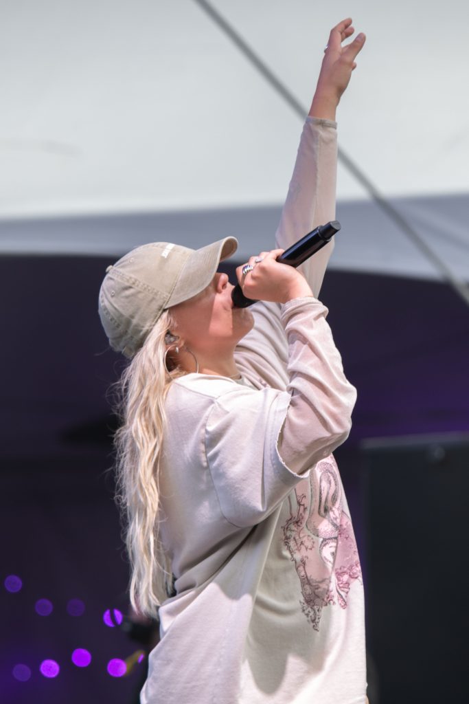 Reneé Rapp reaches up to the sky as she belts some of her popular hits for the crowd at Twin Peaks Stage. Photographed by Caleb Velasquez/BruinLife.