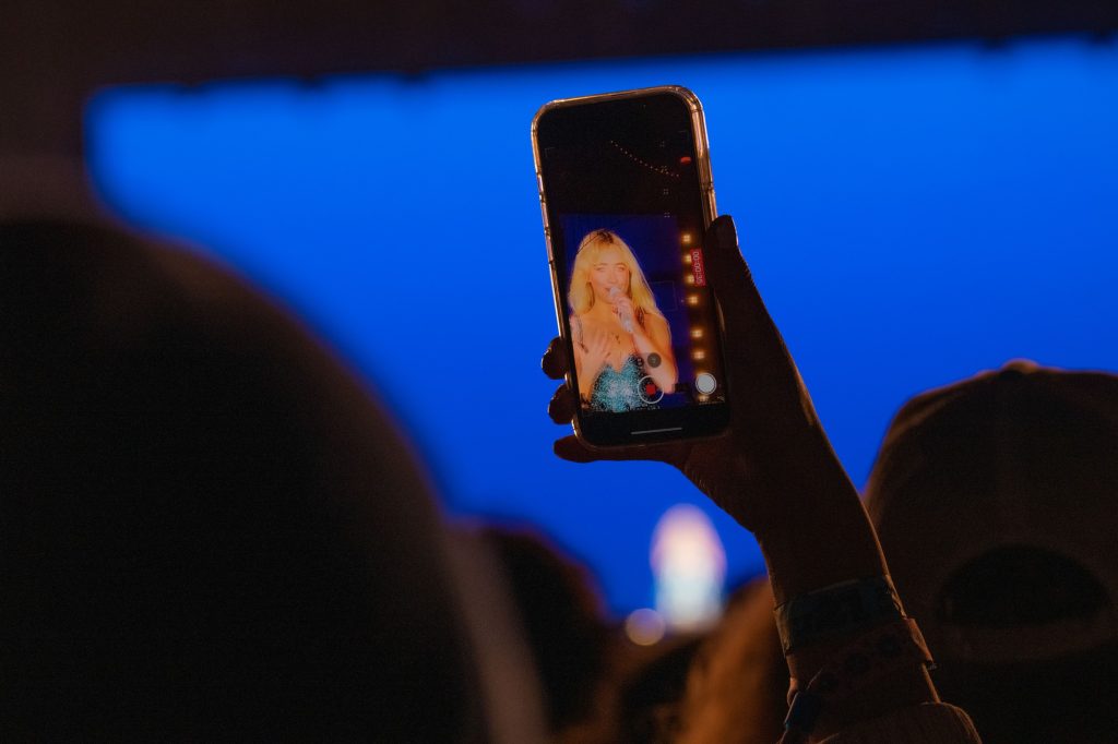 After an outfit change, a fan holds up their phone to record Sabrina Carpenter. Photographed by Caleb Velasquez/BruinLife.