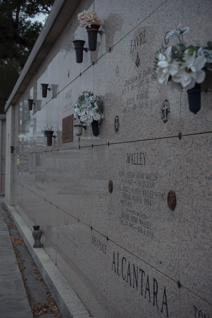 Burial vaults line the wall with placards and flowers for the dead. Some funeral laws in New Orleans were known for their oddness. Photographed by Emily Chandler/BruinLife.