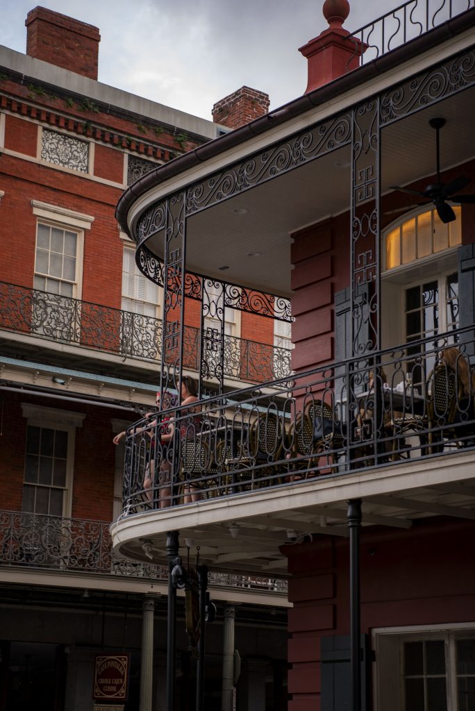 Onlookers watch people flood the streets of the French Quarter. These restaurant balconies were built in New Orleans starting in the 19th century. Photographed by Emily Chandler/BruinLife.