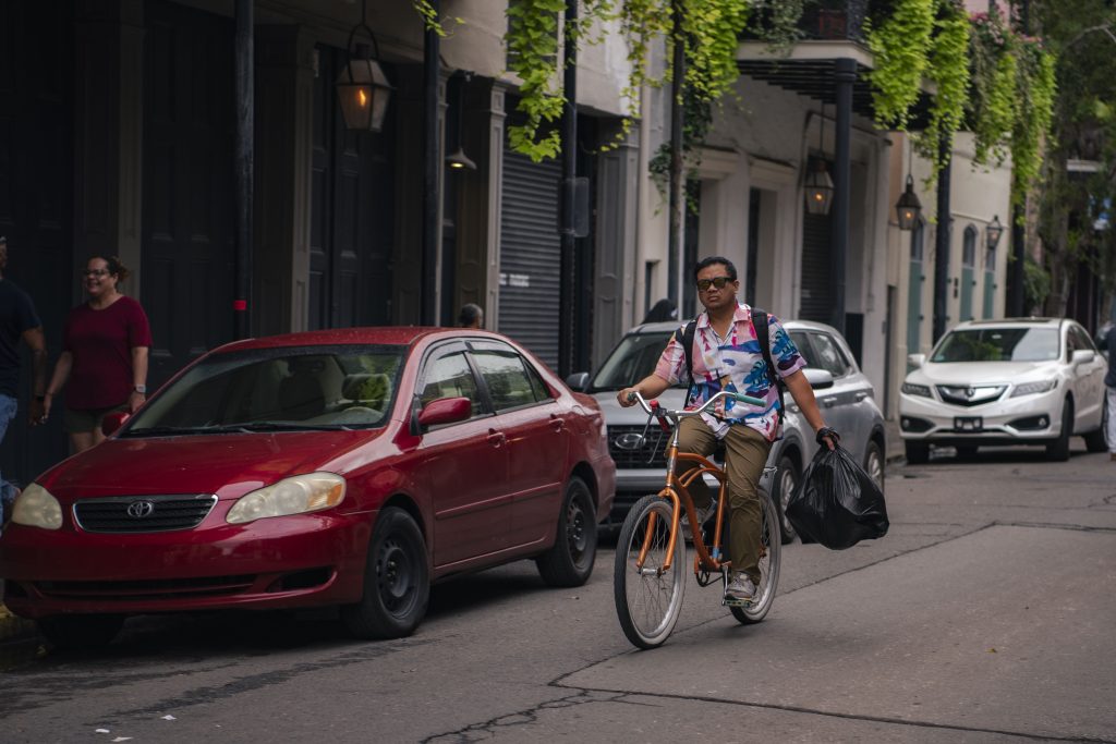 Amongst the partygoers and tourists, a bicyclist rides down Bourban Street in the French Quarter, carrying a trash bag. Due to its narrow roads and slow traffic, the French Quarter is ideal to travel around by bike. Photographed by Emily Chandler/BruinLife.