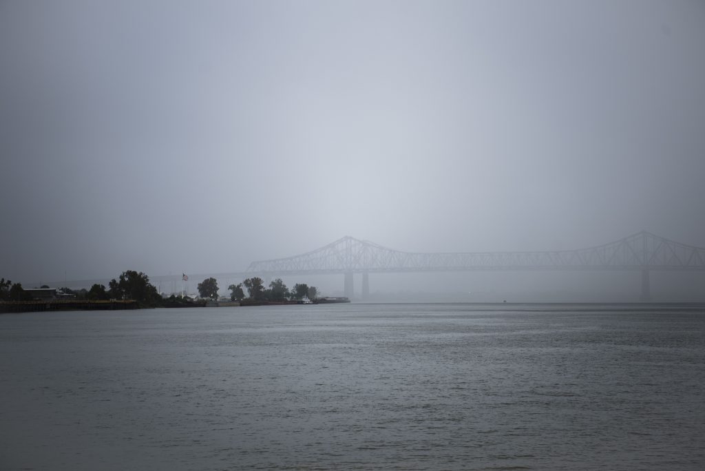 The Greater New Orleans Bridge appears through heavy fog across the Mississippi River. This bridge connects the Garden District and the Fischer Development Neighborhood. Photographed by Emily Chandler/BruinLife.