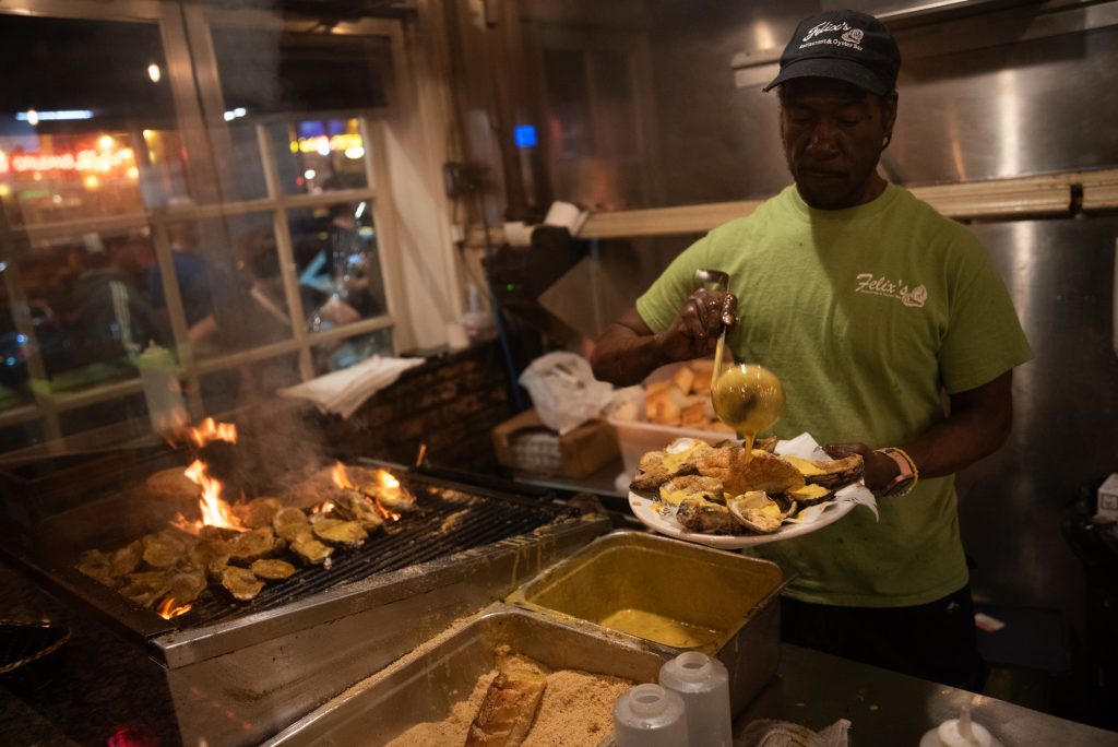 Chef Kevin Scott prepares char-broiled oysters over a flaming grill.  Photographed by Finn Martin/BruinLife.