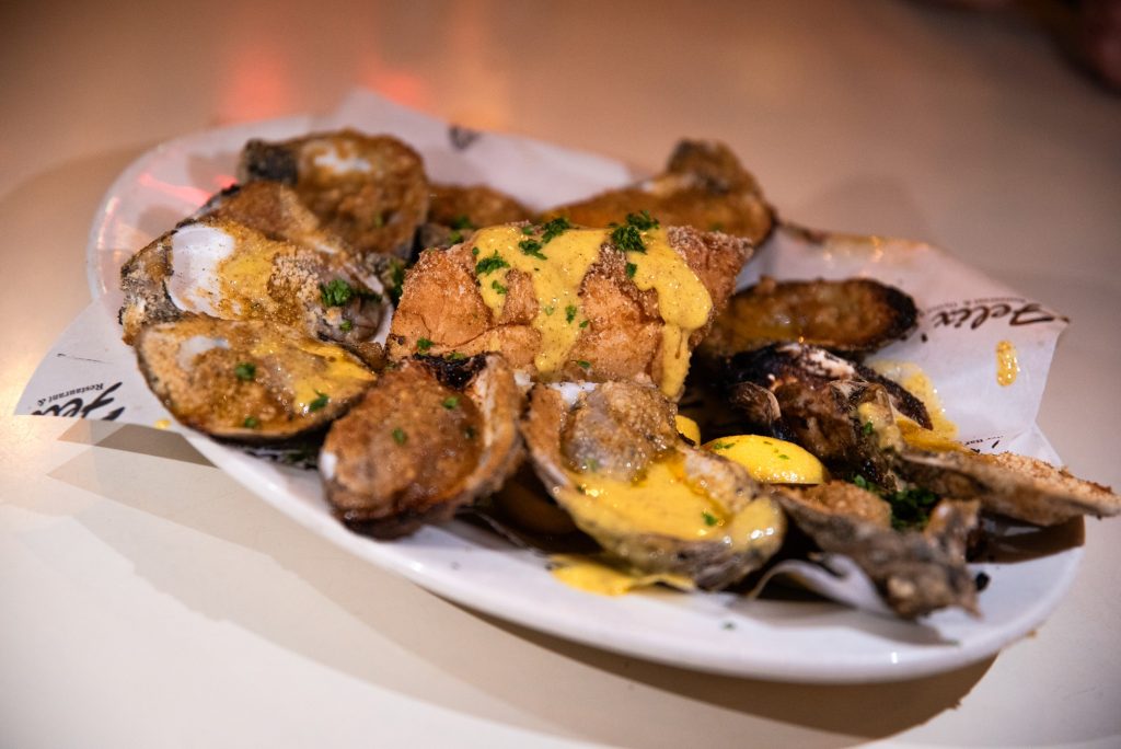 The char-grilled oysters are served with a parmesan sauce and breadcrumbs.  Photographed by Finn Martin/BruinLife.