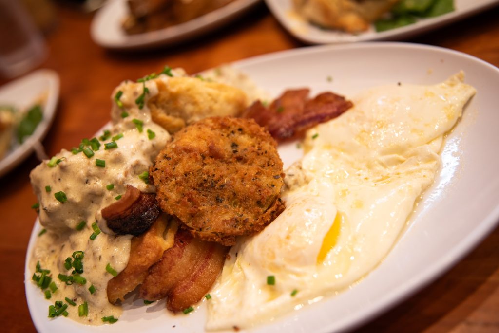 Biscuits and gravy with puffed biscuits, creamy gravy, and a side of bacon and eggs