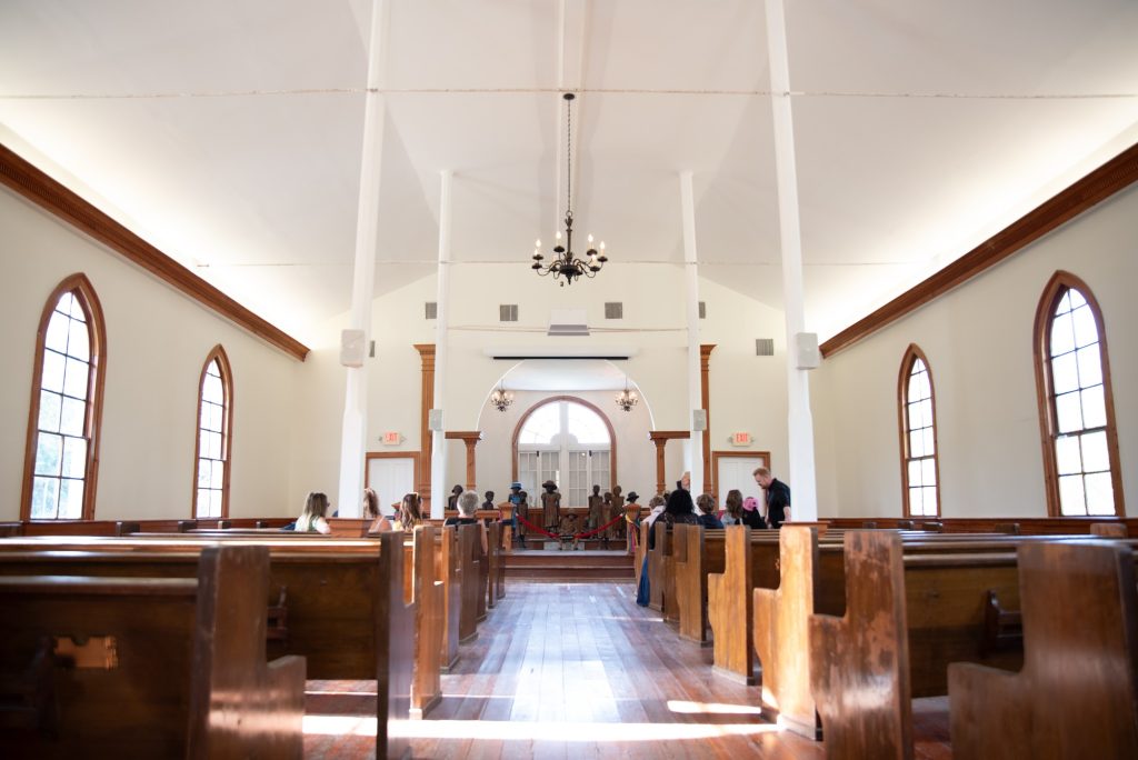 A row of pews inside the Antioch Baptist Church leads to a sculpture exhibit by artist Woodrow Nash. Photographed by Finn Martin/BruinLife.