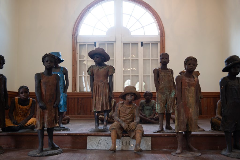 Sculptures of emancipated slave children by artist Woodrow Nash stand in the Antioch Baptist Church.  Because the enslaved were prohibited from looking their enslavers in the eye, Nash purposefully neglected to add eyes to the sculptures.  Photographed by Finn Martin/BruinLife.