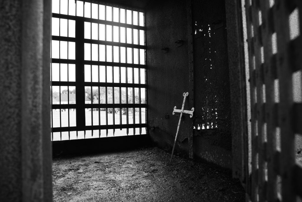 A cross lays against the wall to a jailhouse on the plantation.  Photographed by Finn Martin/BruinLife.