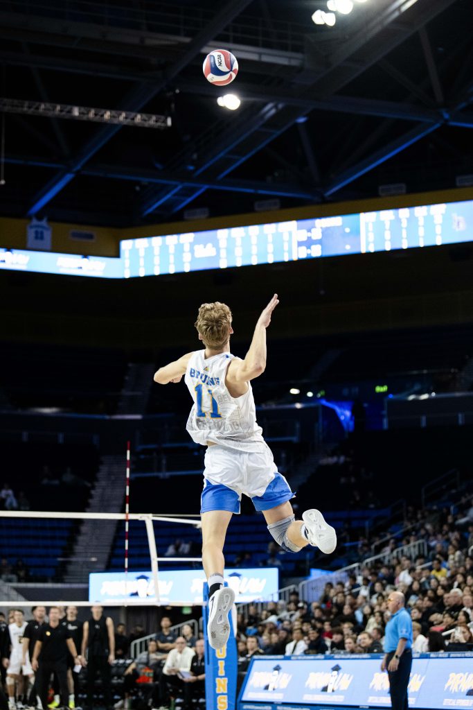 UCLA's outside hitter, Cooper Robinson, launches himself high to deliver a powerful serve. Photographed by Ryan Zhang/BruinLife.