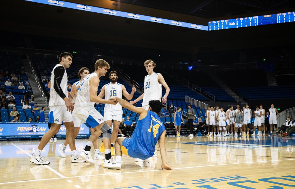 UCLA #11 Cooper Robinson helps up his libero, Matthew Aziz after an attempted save. Photographed by Ryan Zhang/BruinLife