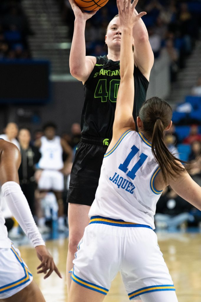 UCLA’s Gabriela Jaquez attempts to block a shot from Michigan State’s Julia Ayrault. The Bruins’ defense remains aggressive, helping them secure the victory.