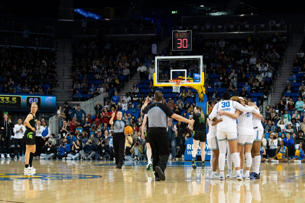 UCLA players huddle in between plays, discussing strategy. The team has been known for its strong communication and focus throughout the season.