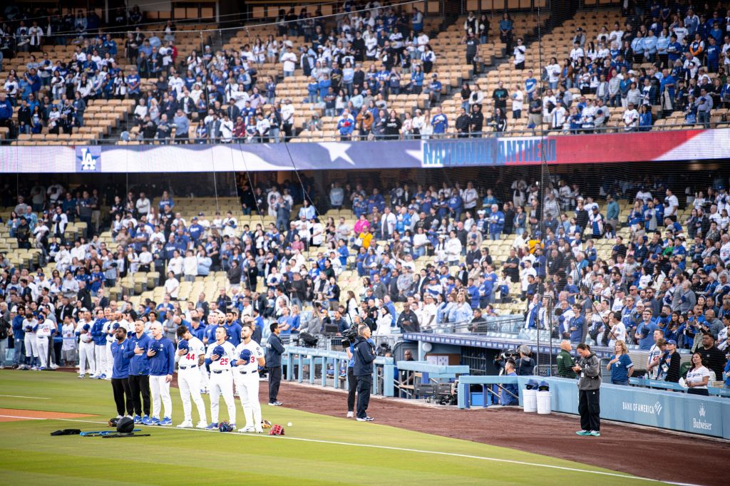 Dodgers and stadium stand to attention, hat in hand, for the national anthem played by guitarist Nita Strauss. Photographed by Finn Martin/BruinLife.