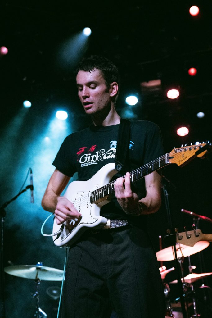 Kai James plays under moody stage lights, locked into the rhythm during the band's opening set. Photographed by Amy Miranda/BruinLife.