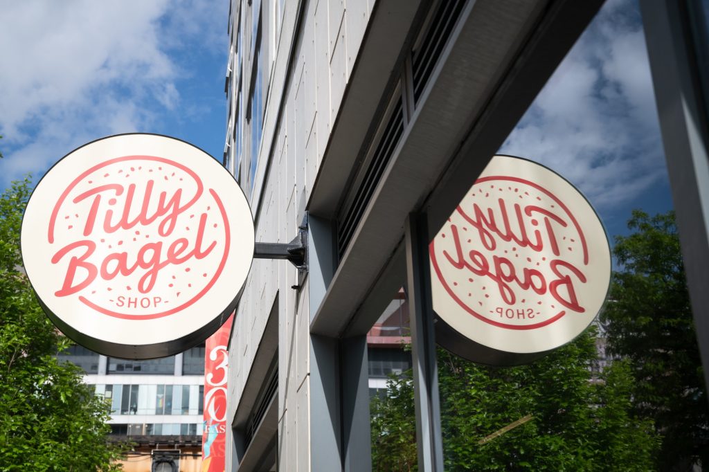 A small sign for a big chain hangs outside the entrance of Tilly Bagel Shop. Photographed by Finn Martin/BruinLife.