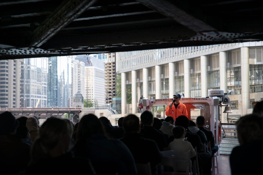 Josh the guide addresses the crowd as we pass underneath another bridge. Keep your arms and legs in the boat at all times else you'll risk it all. Photographed by Finn Martin/BruinLife.