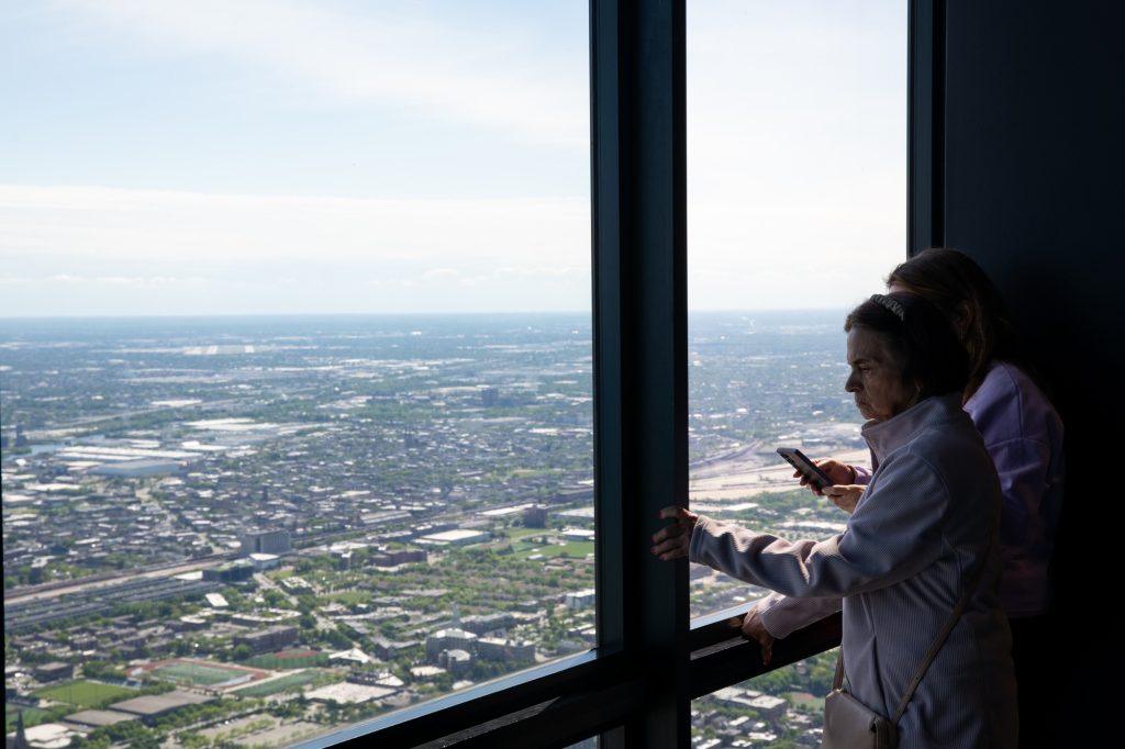 Two people observe the view of Chicago from a window in Willis Tower. Photographed by Finn Martin/BruinLife.