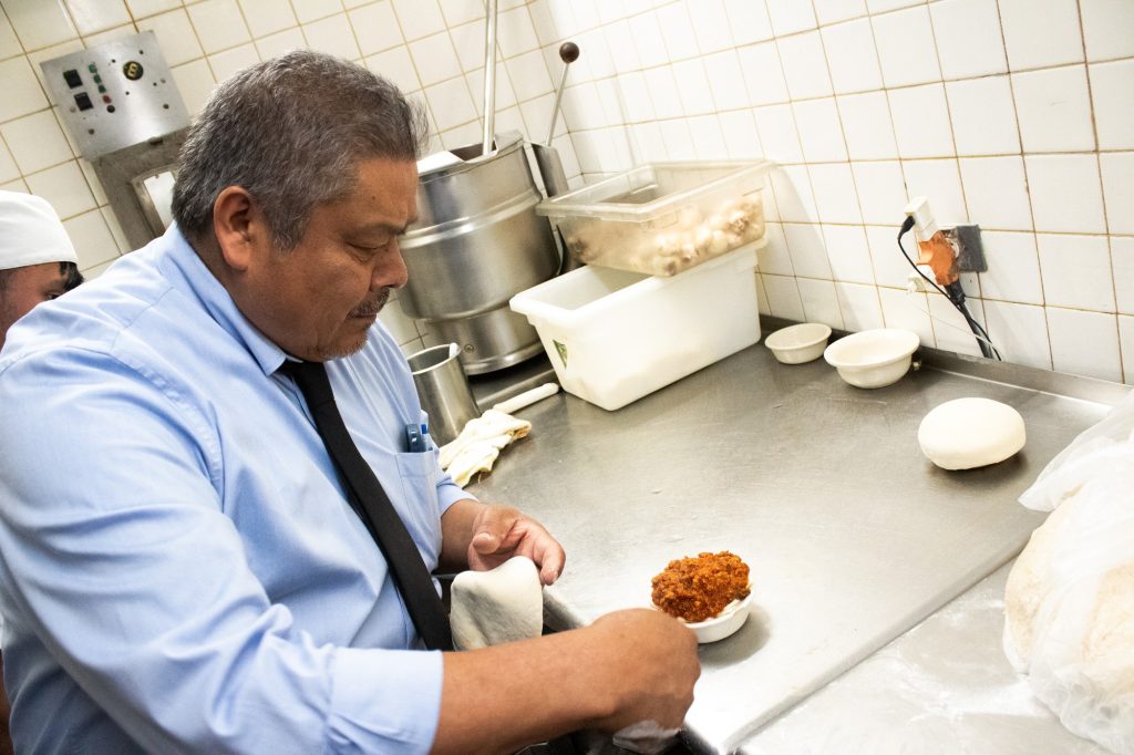 Mariano inspects the filling for the Pizza Pot Pie before delicately wrapping it with dough. Each pizza was given a special sort of pinch to its dough as code for whether or not it is vegetarian, meat, or has mushrooms. Photographed by Finn Martin/BruinLife.